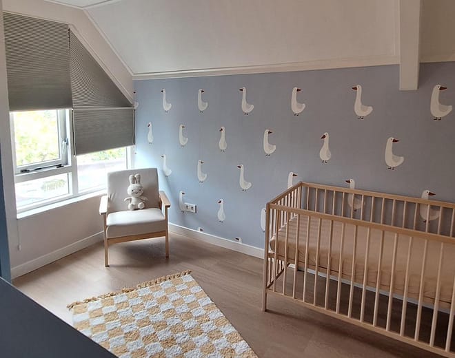 Blauw ganzenbehang in de babykamer